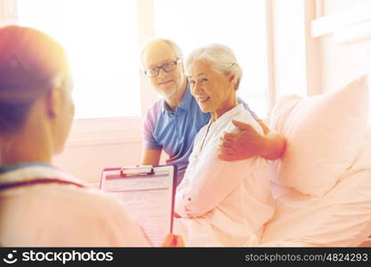 medicine, age, health care and people concept - senior woman, man and doctor with clipboard at hospital ward