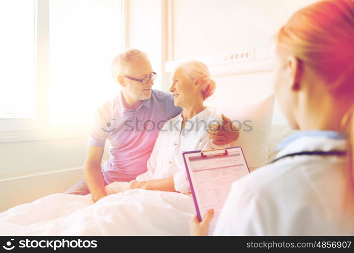 medicine, age, health care and people concept - senior woman, man and doctor with clipboard at hospital ward