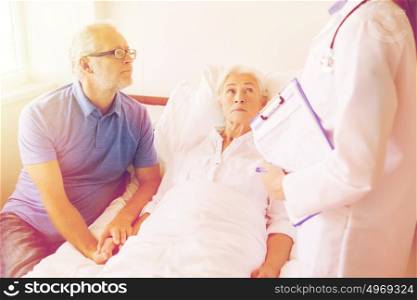 medicine, age, health care and people concept - senior woman, man and doctor with clipboard at hospital ward. senior woman and doctor with clipboard at hospital