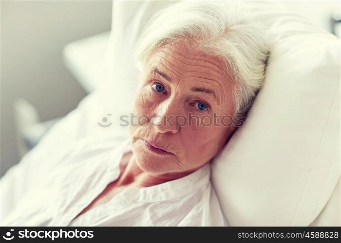 medicine, age, health care and people concept - senior woman patient lying in bed at hospital ward