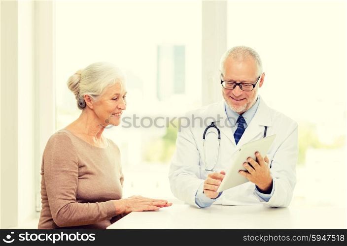 medicine, age, health care and people concept - smiling senior woman and doctor with tablet pc computer meeting in medical office