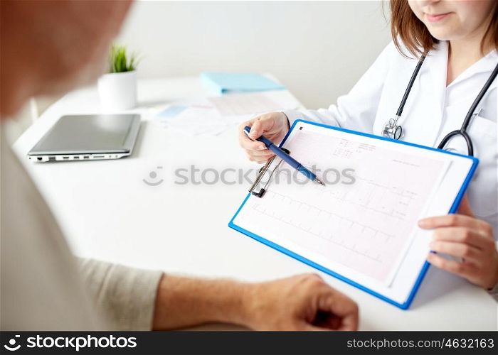 medicine, age, health care, cardiology and people concept - close up of senior man and doctor with cardiogram on clipboard meeting in medical office at hospital