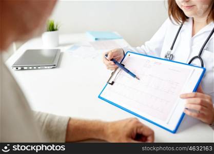 medicine, age, health care, cardiology and people concept - close up of senior man and doctor with cardiogram on clipboard meeting in medical office at hospital