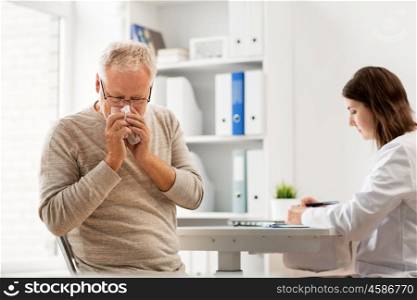 medicine, age, health care, flu and people concept - senior man blowing nose with napkin and doctor with clipboard writing at medical office at hospital