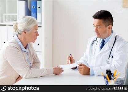 medicine, age, healthcare and people concept - senior woman and doctor with prescription or referral at hospital. woman and doctor with prescription at clinic