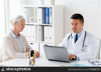 medicine, age, healthcare and people concept - smiling senior woman and doctor with laptop computer meeting at hospital. senior woman and doctor with laptop at hospital