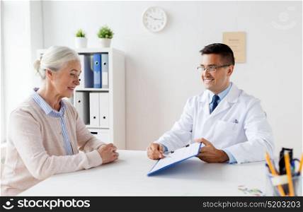 medicine, age, healthcare and people concept - smiling senior woman and doctor with clipboard meeting at hospital. senior woman and doctor meeting at hospital
