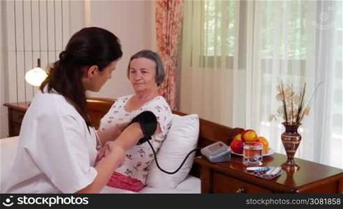 Medicine, age, support, health care and people concept - doctor or nurse with stethoscope visiting senior woman and checking her breath or heartbeat at home. Slow motion hand held movement