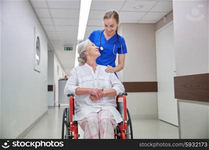 medicine, age, support, health care and people concept - happy nurse taking senior woman patient in wheelchair at hospital corridor