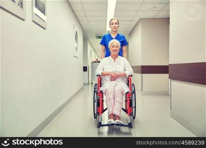 medicine, age, support, health care and people concept - nurse taking senior woman patient in wheelchair at hospital corridor