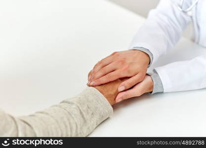 medicine, age, support, healthcare and people concept - close up of doctor or nurse holding senior man hand at hospital