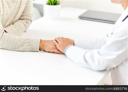 medicine, age, support, healthcare and people concept - close up of doctor or nurse holding senior man hand at hospital