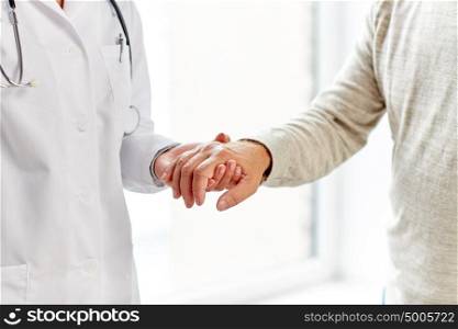 medicine, age, support, healthcare and people concept - close up of doctor or nurse holding senior man hand at hospital. close up of doctor holding old man hand