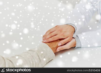 medicine, age, support, healthcare and people concept - close up of doctor or nurse holding senior man hand at hospital over snow. close up of doctor holding old man hand