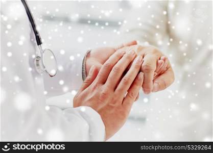 medicine, age, support, healthcare and people concept - close up of doctor or nurse holding senior man hand at hospital over snow. close up of doctor holding old man hand