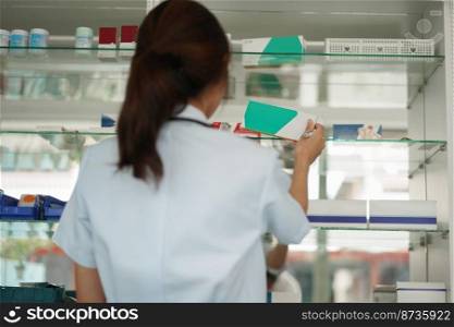 Medicine and health concept, Female pharmacist hold medicine box to checklist in paper at drugstore.