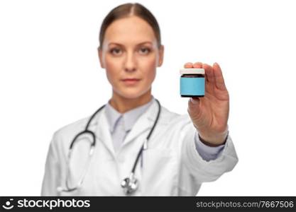 medicine and healthcare concept - close up of female doctor with stethoscope holding jar of pills over white background. female doctor holding jar of medicine