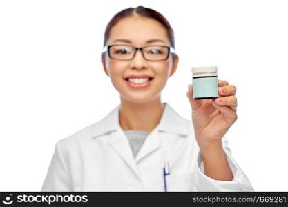 medicine and healthcare concept - close up of happy smiling asian female doctor holding jar of pills over white background. smiling female doctor holding jar of medicine