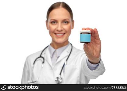 medicine and healthcare concept - close up of happy smiling female doctor with stethoscope holding jar of pills over white background. smiling female doctor holding jar of medicine