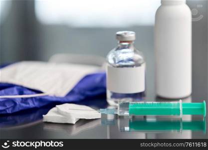 medicine and healthcare concept - close up of syringe, drug, wound wipes, gloves and mask on table. syringe, medicine, wound wipes, gloves and mask