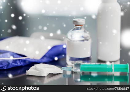 medicine and healthcare concept - close up of syringe, drug, wound wipes, gloves and mask on table in winter over snow. syringe, medicine, wound wipes, gloves and mask