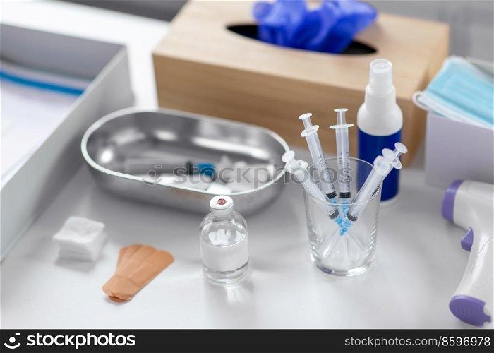 medicine and healthcare concept - close up of syringes, drug in jar and other stuff on table at hospital. syringes, medicine and other stuff on table