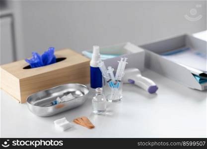 medicine and healthcare concept - close up of syringes, drug in jar and other stuff on table at hospital. syringes, medicine and other stuff on table