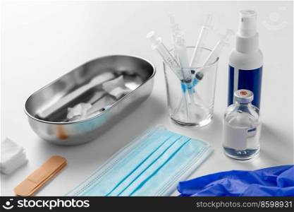 medicine and healthcare concept - close up of syringes, gloves, mask and other medical stuff on table at hospital. syringes, mask, gloves and other stuff on table