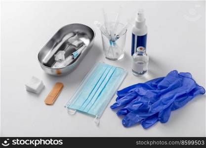 medicine and healthcare concept - close up of syringes, gloves, mask and other medical stuff on table at hospital. syringes, mask, gloves and other stuff on table