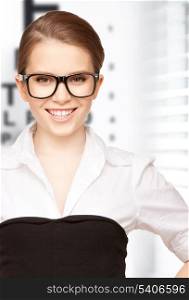 medicine and vision concept - woman in eyeglasses with eye chart