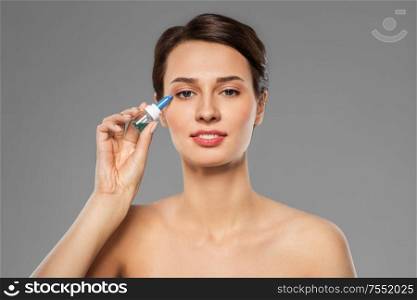 medicine, beauty and vision people concept - portrait of beautiful young woman with eye drops over grey background. beautiful young woman with eye drops