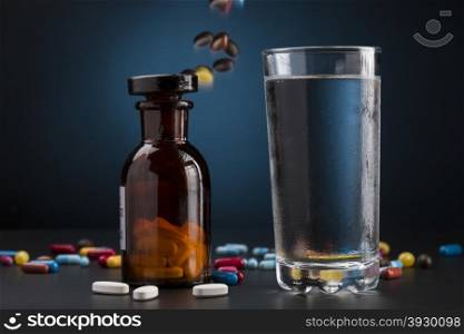 Medicine bottle pills colorful and glass of drink water. Medicine bottle pills and glass of cold drink water