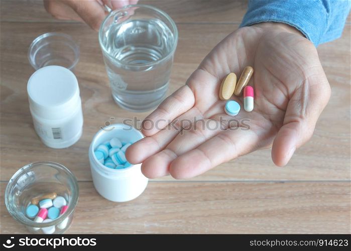 Medicine capsules (assorted pills) in a man's hand.wood background. Concept of self-medication, health, depression, diabetes, Have a fever, medications