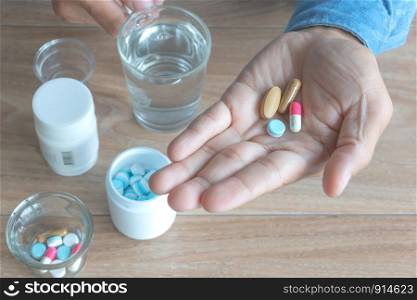 Medicine capsules (assorted pills) in a man's hand.wood background. Concept of self-medication, health, depression, diabetes, Have a fever, medications