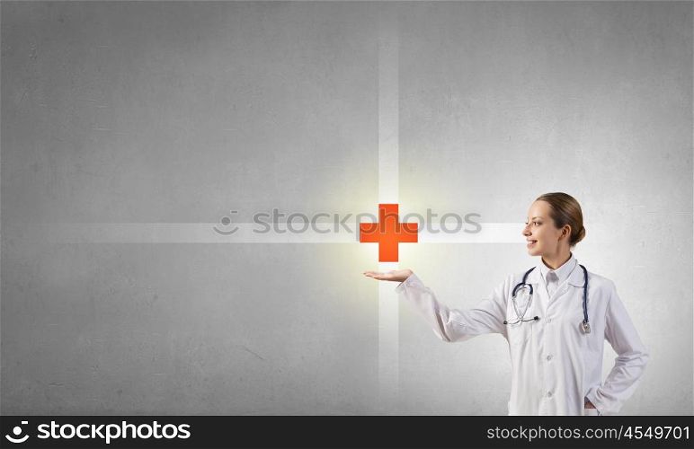 Medicine cross symbol. Attractive female doctor in white showing medicine cross sign