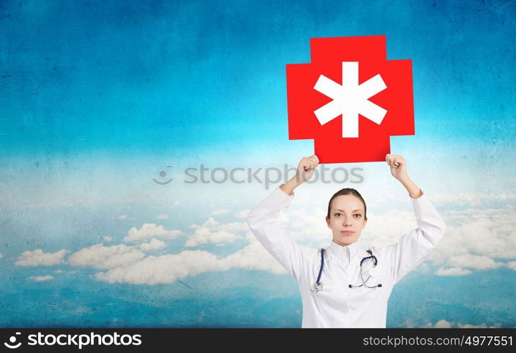 Medicine cross symbol. Attractive female doctor in white showing medicine cross sign