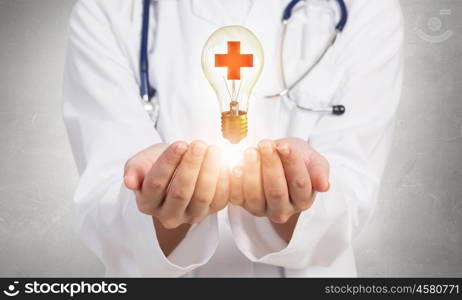 Medicine cross symbol. Female doctor in white showing light bulb with medicine cross sign