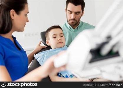 medicine, dentistry and healthcare concept - father and son visiting dentist at dental clinic. father and son visiting dentist at dental clinic. father and son visiting dentist at dental clinic