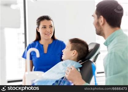 medicine, dentistry and healthcare concept - father and son visiting dentist at dental clinic. father and son visiting dentist at dental clinic. father and son visiting dentist at dental clinic