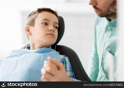 medicine, dentistry and healthcare concept - father supporting son at dental clinic. father supporting son at dental clinic. father supporting son at dental clinic