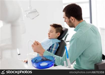 medicine, dentistry and healthcare concept - father supporting son at dental clinic. father supporting son at dental clinic. father supporting son at dental clinic
