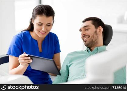 medicine, dentistry and healthcare concept - female dentist showing tablet pc computer to male patient at dental clinic office. dentist and patient with tablet pc at clinic. dentist and patient with tablet pc at clinic