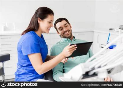 medicine, dentistry and healthcare concept - female dentist with tablet pc computer and male patient discussing teeth treatment at dental clinic office. dentist and patient with tablet pc at clinic. dentist and patient with tablet pc at clinic