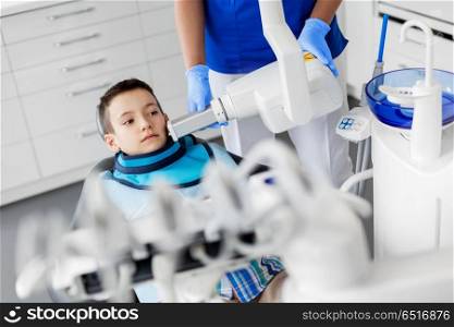 medicine, dentistry and healthcare concept - female dentist with x-ray machine scanning kid patient teeth at dental clinic. dentist making x-ray of kid teeth at dental clinic. dentist making x-ray of kid teeth at dental clinic