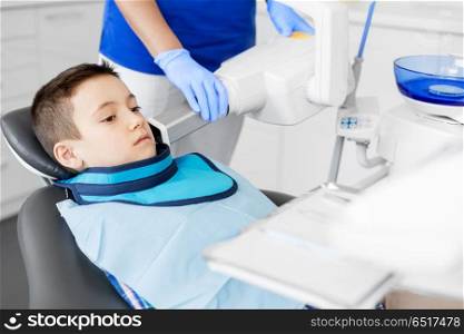 medicine, dentistry and healthcare concept - female dentist with x-ray machine scanning kid patient teeth at dental clinic. dentist making x-ray of kid teeth at dental clinic. dentist making x-ray of kid teeth at dental clinic