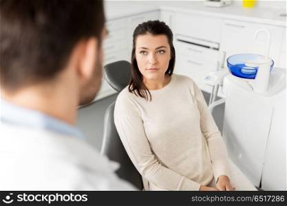 medicine, dentistry and healthcare concept - female patient talking to dentist at dental clinic office. female patient talking to dentist at dental clinic. female patient talking to dentist at dental clinic
