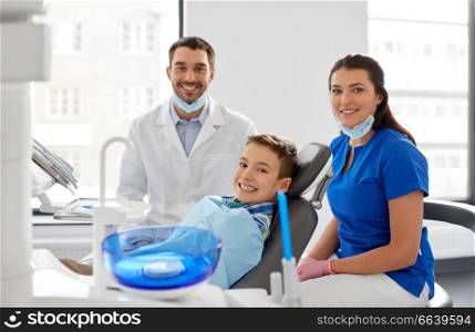 medicine, dentistry and healthcare concept - happy dentist, assistant and kid patient at dental clinic. dentists and kid patient at dental clinic