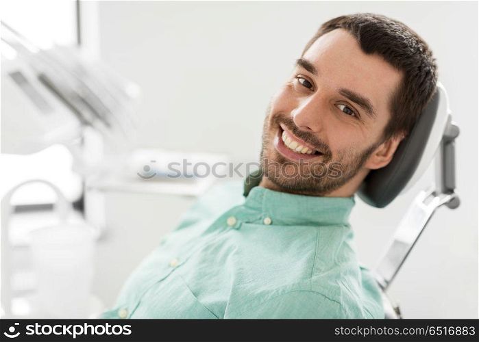 medicine, dentistry and healthcare concept - happy smiling male patient on chair at dental clinic. happy smiling male patient at dental clinic. happy smiling male patient at dental clinic