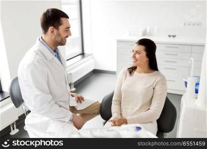 medicine, dentistry and healthcare concept - male dentist talking to female patient and discussing teeth treatment at dental clinic office. dentist talking to female patient at dental clinic. dentist talking to female patient at dental clinic