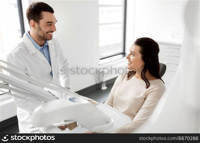 medicine, dentistry and healthcare concept - male dentist talking to female patient and discussing teeth treatment at dental clinic office. dentist talking to female patient at dental clinic. dentist talking to female patient at dental clinic